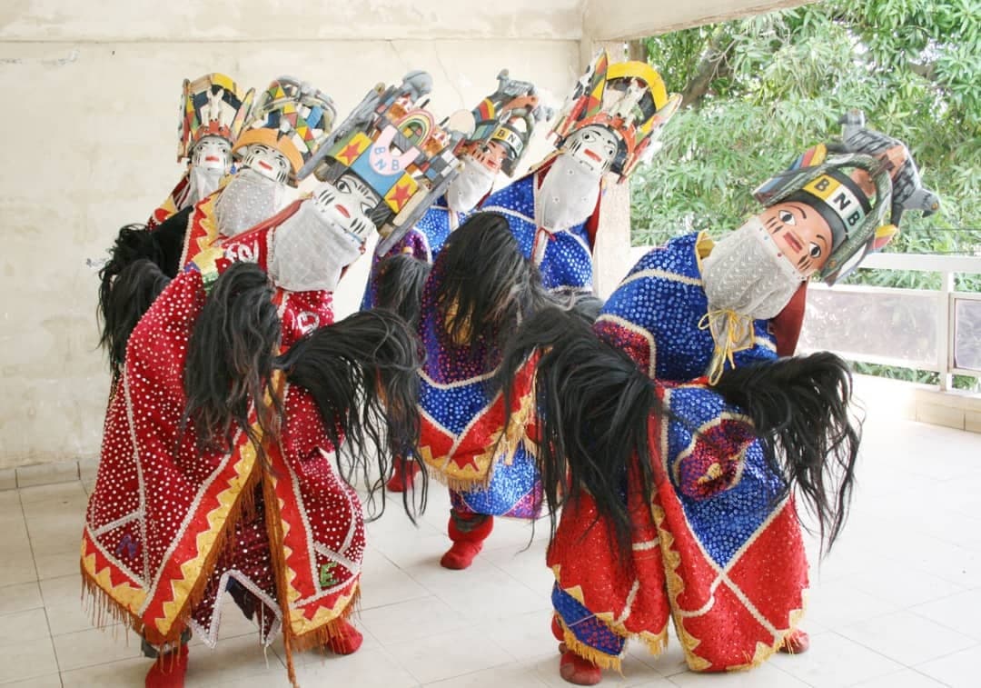 Masked dancers in embroidered red and blue costumes