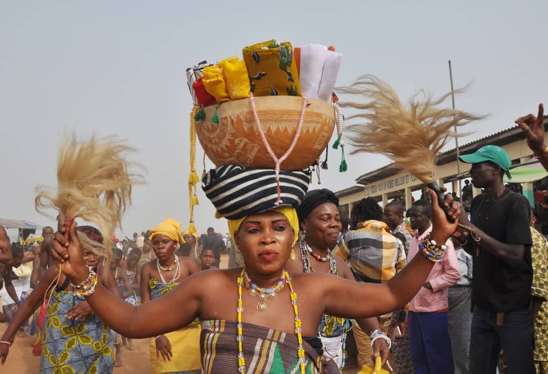 A dancer carrying a calabash of offerings on her head