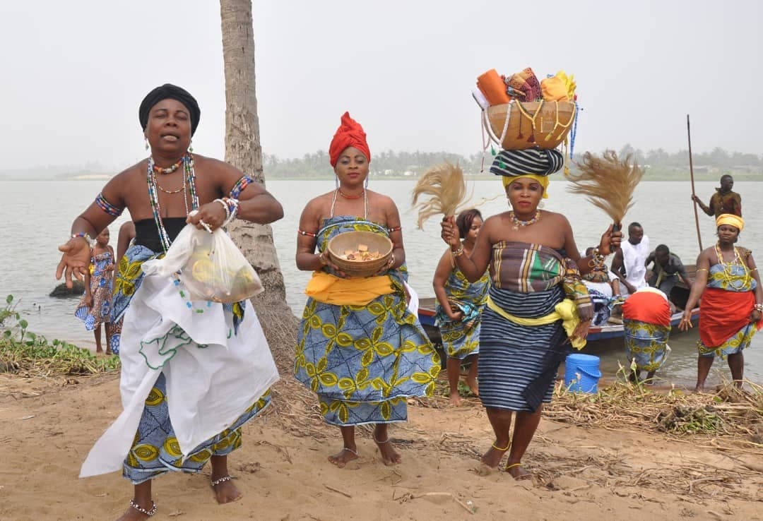 Femmes portant des offrandes au bord de la lagune
