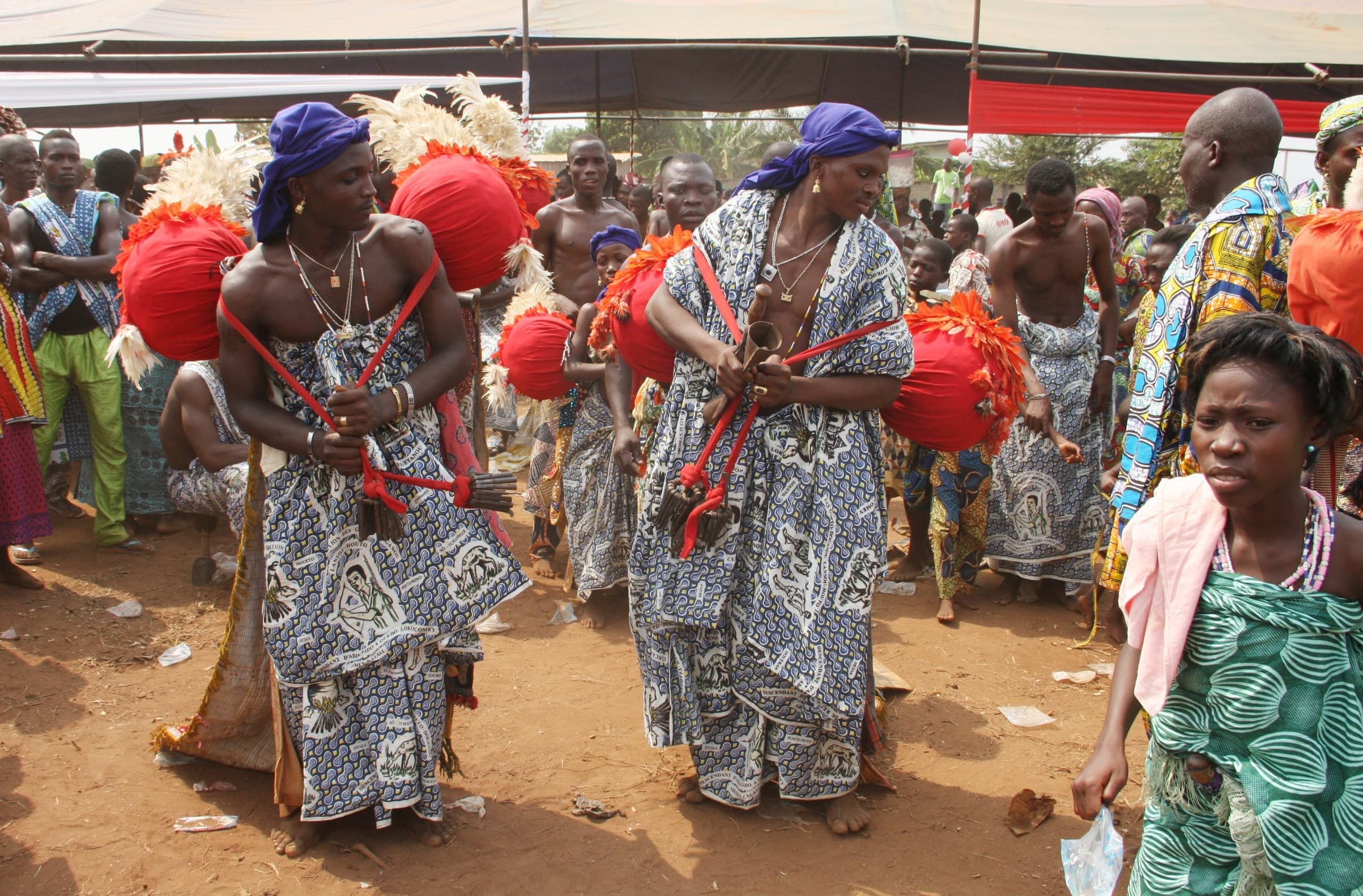 Devotees dancing during a Vodun Days ceremony, with red pompoms and headdresses